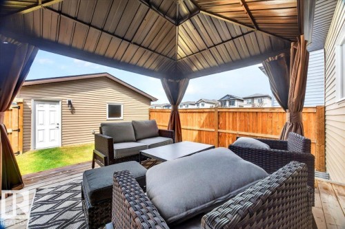 Covered outdoor deck area featuring a durable wood-finish surface, a substantial metal gazebo structure, and privacy curtains - 424 Black Stone Link, Leduc, AB 