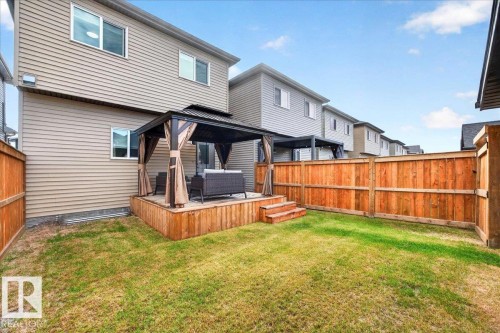 Private backyard featuring a wooden deck with a built-in gazebo, a manicured lawn, and a perimeter wood fence - 424 Black Stone Link, Leduc, AB 
