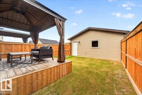 Elevated wood-plank deck with a covered gazebo structure featuring privacy curtains - 424 Black Stone Link, Leduc, AB 
