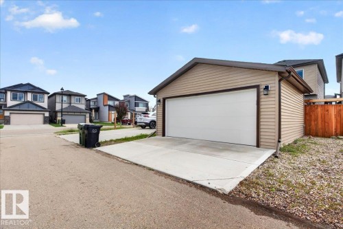 Detached garage featuring light-colored horizontal siding, a white overhead door, and dark trim - 424 Black Stone Link, Leduc, AB 