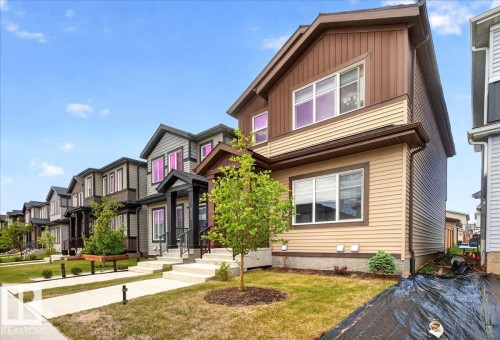 Contemporary two-story exterior featuring multi-toned siding, a covered entry, and a manicured lawn - 424 Black Stone Link, Leduc, AB 