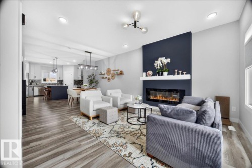 Open-concept living space featuring wood-finish flooring, recessed lighting, and a linear electric fireplace with a contrasting accent wall - 424 Black Stone Link, Leduc, AB 