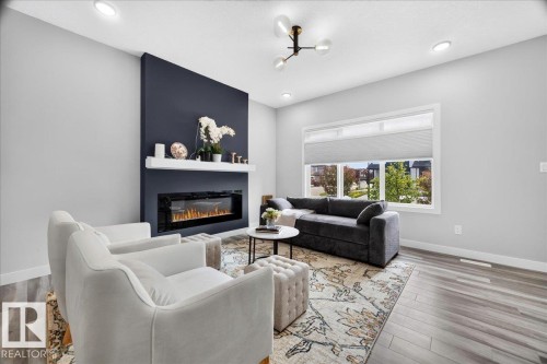 Living space featuring a fireplace with a dark accent wall, a white mantel, and a long electric insert - 424 Black Stone Link, Leduc, AB 