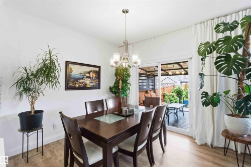 Dining area with wood-finish flooring, white walls, and a contemporary chandelier - 9323 223 Street, Edmonton, AB 