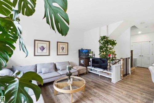 Living area featuring wood-finish flooring, white walls, and a staircase with a wooden handrail - 9323 223 Street, Edmonton, AB 