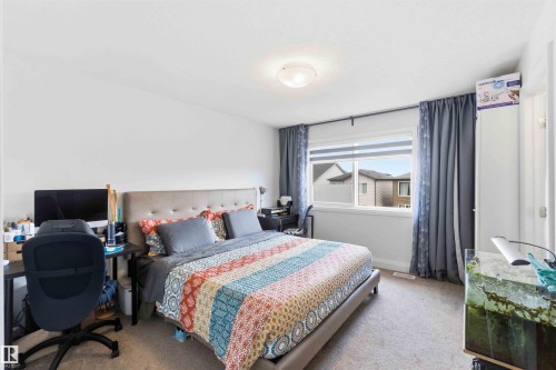 Spacious bedroom featuring light-colored walls, a large window, and carpeted flooring - 9323 223 Street, Edmonton, AB 