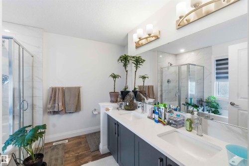 Spacious bathroom featuring a dual vanity with undermount sinks, a large mirror, and two wall-mounted light fixtures - 9323 223 Street, Edmonton, AB 