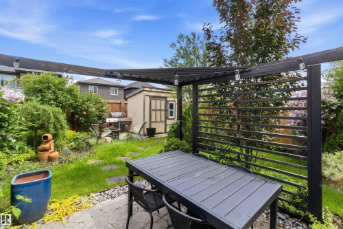 Private outdoor patio with a black slatted pergola and string lighting - 9323 223 Street, Edmonton, AB 