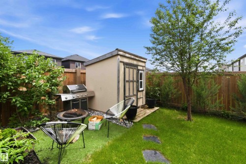 Fenced backyard featuring a storage shed, established tree, and stepping stone path - 9323 223 Street, Edmonton, AB 