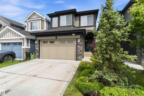 Contemporary exterior featuring mixed material siding, a two-car garage, and a landscaped front yard with mature plantings - 9323 223 Street, Edmonton, AB 