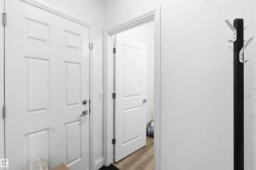Entryway featuring a paneled door with brushed nickel hardware, light wood-finish flooring, and a white wall finish - 9323 223 Street, Edmonton, AB 