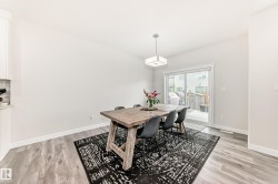 Dining area featuring wood-finish flooring, a contemporary ceiling light fixture, a built-in cabinet with a stone countertop, and sliding glass doors providing outdoor access - 