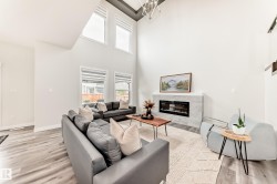 Vaulted living space featuring high ceilings, wood-finish flooring, and an electric fireplace with a stone surround - 