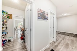 Hallway with light wood-finish flooring, white walls, and recessed lighting - 