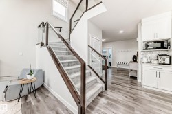 Modern staircase featuring a glass and wood-finish railing, carpeted treads, and a prominent window - 