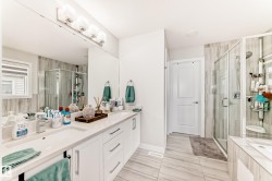 Bathroom featuring a double vanity with stone countertops, white shaker cabinetry, and dual undermount sinks - 