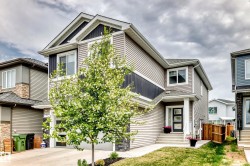 Contemporary two-story exterior featuring siding in varied tones, a black panel garage door, and a covered entry with a multi-pane door - 