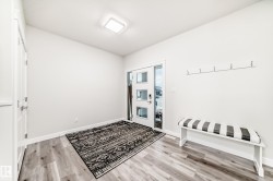 Entryway featuring wood-finish flooring, a modern square ceiling light fixture, and a white paneled door with rectangular glass inserts - 