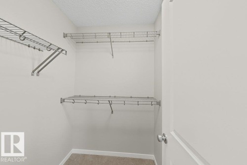 Interior closet featuring white walls, textured ceiling, and carpeted flooring - 5034 Rivers Edge Way, Edmonton, AB 