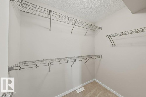 Walk-in closet with ample wire shelving, neutral carpeting, and light-toned walls - 5034 Rivers Edge Way, Edmonton, AB 