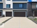 Contemporary multi-level facade featuring blue and white horizontal siding, black-framed windows, and a dark garage door - 5034 Rivers Edge Way, Edmonton, AB 