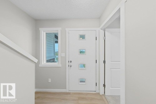 Entryway featuring a contemporary white door with square window inserts, wood-finish flooring, a side window, and white trim - 5034 Rivers Edge Way, Edmonton, AB 