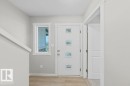 Entryway featuring a contemporary white door with square window inserts, wood-finish flooring, a side window, and white trim - 5034 Rivers Edge Way, Edmonton, AB 