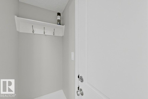 Entryway featuring a white built-in shelf with three coat hooks and a light gray painted wall - 5034 Rivers Edge Way, Edmonton, AB 