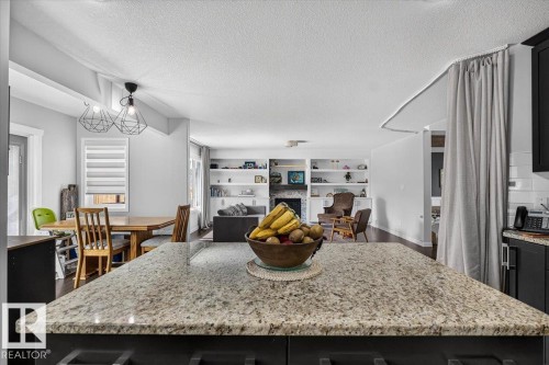 Granite countertop island with dark cabinetry provides a central kitchen feature - 13 Baie Madelene, Beaumont, AB 