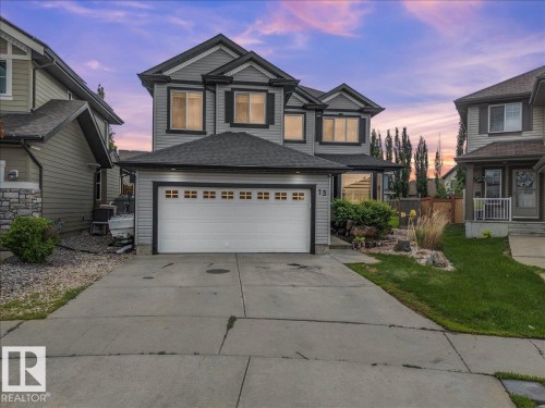 Two-story residence featuring grey siding, dark trim, and a two-car attached garage with decorative windows - 13 Baie Madelene, Beaumont, AB 
