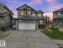 Two-story residence featuring grey siding, dark trim, and a two-car attached garage with decorative windows - 13 Baie Madelene, Beaumont, AB 
