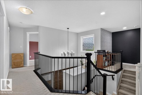 Upper landing featuring black metal railings and a contemporary chandelier - 13 Baie Madelene, Beaumont, AB 