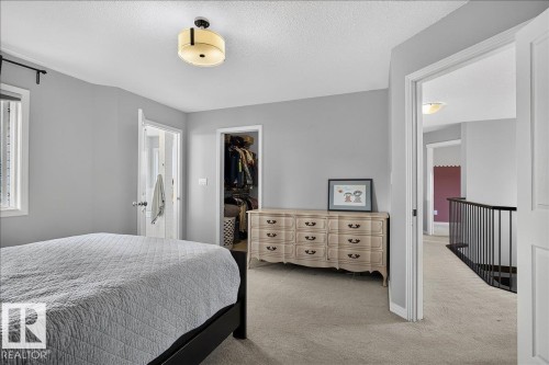 Carpeted room featuring a ceiling-mounted light fixture, white trim, and a window with blinds - 13 Baie Madelene, Beaumont, AB 