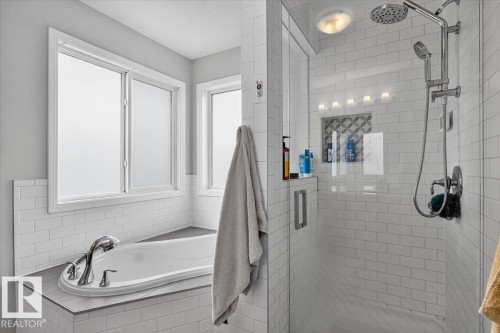 Contemporary bathroom featuring a built-in soaking tub with polished chrome fixtures and a surrounding tile half-wall - 13 Baie Madelene, Beaumont, AB 