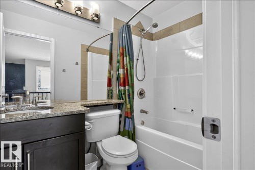 Bathroom featuring a dark wood vanity with a granite-style countertop, undermount sink, and chrome fixtures - 13 Baie Madelene, Beaumont, AB 