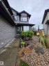 Two-story residence featuring light gray siding with dark trim, a dark green entry door, and a bay window - 13 Baie Madelene, Beaumont, AB 