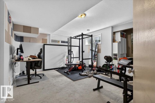 Versatile room featuring light grey walls, recessed windows with blinds, built-in white cabinetry, and carpeted flooring - 13 Baie Madelene, Beaumont, AB 