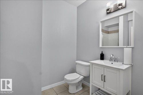 Bathroom featuring a white vanity with integrated sink, chrome faucet, and a wall-mounted mirror - 13 Baie Madelene, Beaumont, AB 