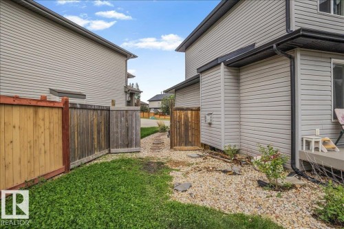 Property exterior featuring light gray horizontal siding, black downspouts, and black eavestroughs - 13 Baie Madelene, Beaumont, AB 