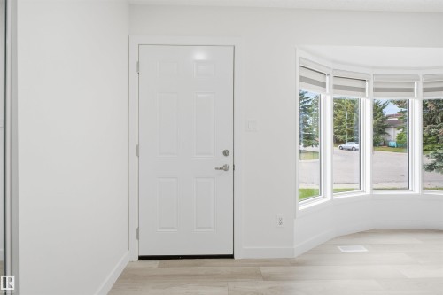 Entryway featuring a white paneled door, light wood-finish flooring, and a curved bay window with multiple panes - 3548 20 Ave, Edmonton, AB 