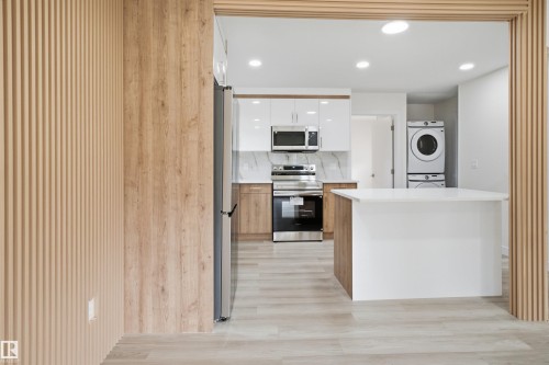 Modern kitchen featuring a white countertop island, stainless steel appliances, wood-finish cabinetry, and recessed lighting - 3548 20 Ave, Edmonton, AB 