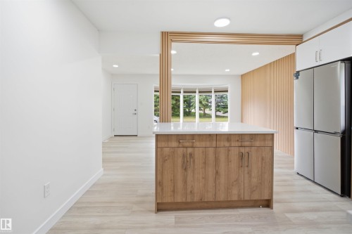 Kitchen island with a light wood-finish base, white countertop, and stainless steel hardware - 3548 20 Ave, Edmonton, AB 