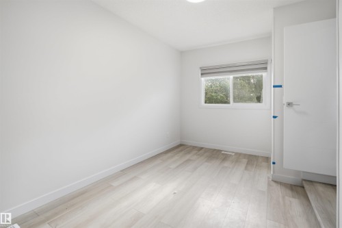 Bright room featuring wood-finish flooring, white baseboards, and a window with a roller blind - 3548 20 Ave, Edmonton, AB 