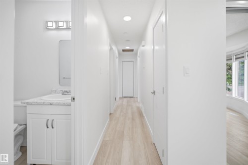 Bright hallway with recessed lighting, wood-finish flooring, and multiple doorways - 3548 20 Ave, Edmonton, AB 