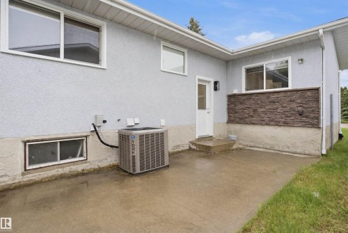 Central A/C- Exterior featuring stucco siding, white-framed windows, and an air conditioning unit - 3548 20 Ave, Edmonton, AB 