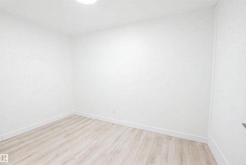 Light wood-finish flooring complements crisp white walls and baseboards - 3548 20 Ave, Edmonton, AB 