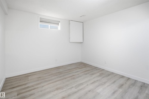 Bright interior space featuring light wood-finish flooring, white baseboards, and a window with a roller shade - 3548 20 Ave, Edmonton, AB 