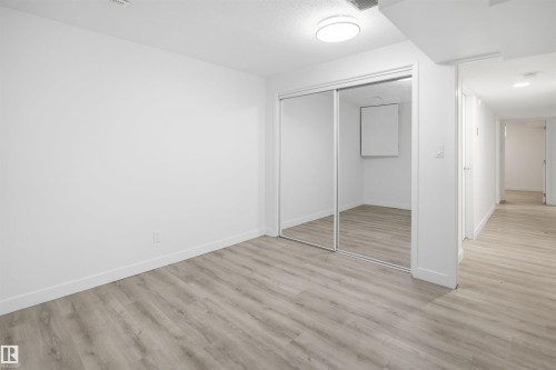 Room featuring wood-finish flooring, a flush-mount ceiling light, and white painted walls - 3548 20 Ave, Edmonton, AB 