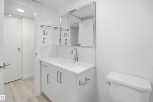 White vanity with chrome hardware, an integrated sink, and a stone-finish countertop - 3548 20 Ave, Edmonton, AB 