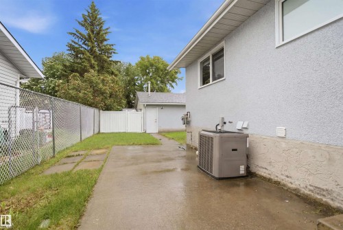 Concrete patio with a chain-link fence bordering a grassy area - 3548 20 Ave, Edmonton, AB 